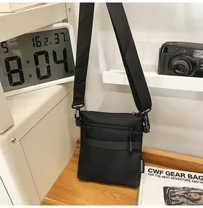 Detail of a black nylon crossbody bag with zipper pockets and techwear tactical straps