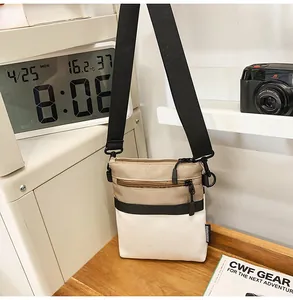 Detailed view of canvas crossbody bag with three-color stitching and double zippers
