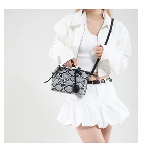 Detail view of snakeskin pattern handbag styled on model with white studio background