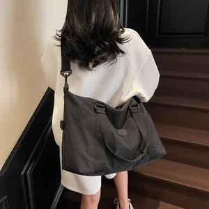 Black nylon travel duffel bag with shoulder strap shown from a back perspective