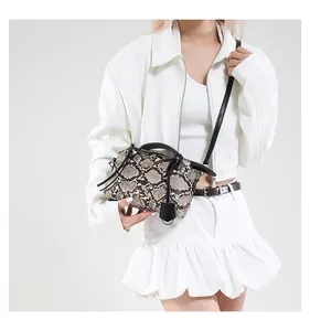 Detail of snakeskin print handbag worn with white outfit for stylish fashion look