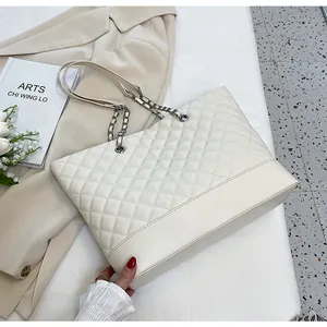 Detailed view of beige quilted tote bag with silver chain strap in elegant setting