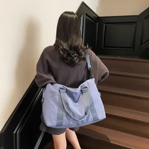 Minimalist light blue canvas travel bag shown on a model, featuring a large capacity design