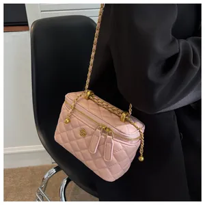 Detail of light pink quilted leather cosmetic bag with gold floral logo and chain strap