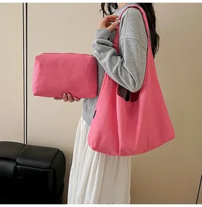 Pink canvas tote bag and matching zipper pouch set shown with a model on a sofa