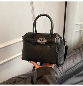 Dettaglio borsa a mano in pelle martellata nera con chiusura a scatto metallica fine