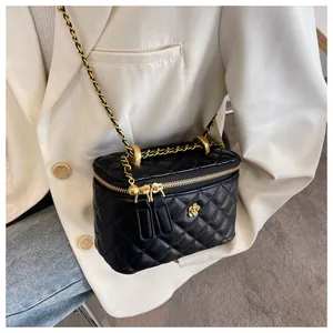 Detail of black quilted leather crossbody bag with gold flower clasp and chain strap