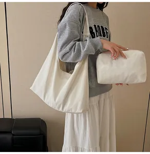Detail view of beige canvas tote bag and matching zipper pouch shown on model shoulder