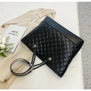 Close-up of black quilted oxford tote bag with silver chain straps in lifestyle setting