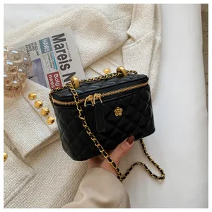 Detailed close-up of black quilted crossbody cosmetic bag with gold chain strap