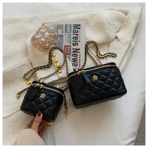Detail of black quilted leather handbags with gold chain straps and floral metal accents