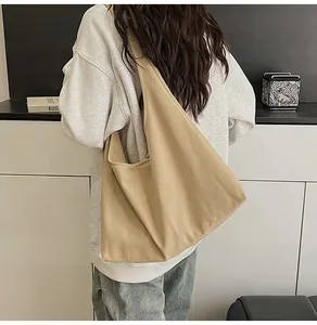 Detail of minimalist beige canvas tote bag showing wide shoulder strap and large capacity