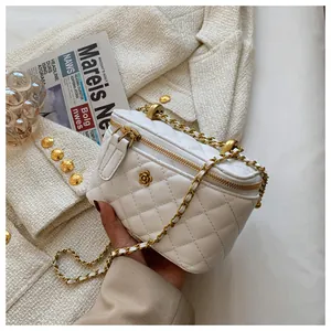 Detail of white quilted crossbody bag featuring golden camellia clasp and chain strap