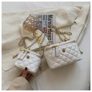 Detail showing two white quilted leather vanity bags with gold chains and floral logo