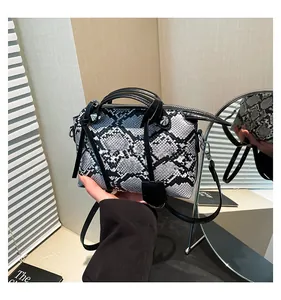 Detailed view of snakeskin pattern handbag with metallic studs and black leather handle