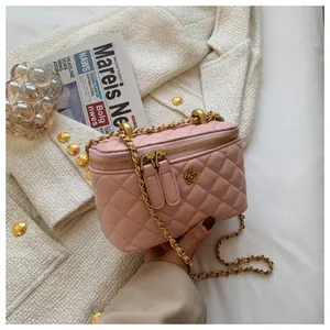 Detail of pink quilted crossbody bag with golden chain and floral logo on textured leather