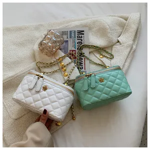 Close-up of quilted cross-body cosmetic bags in white and mint green with gold flower