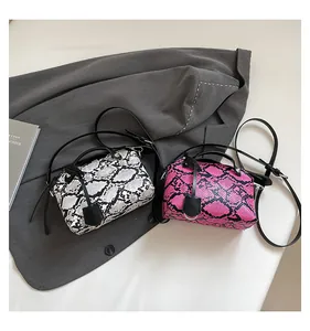 Detail of snake skin pattern mini handbags in black and pink on a grey blazer