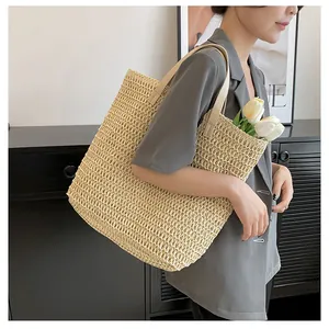 Large beige straw tote bag with leather straps worn by model for beach vacation style