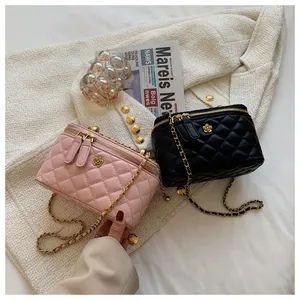 Detail of pink and black quilted chain makeup bags with gold flower accents and PU leather