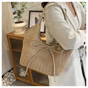 Détail d'un sac cabas en paille avec nœud en cuir et fine bandoulière pour l'été
