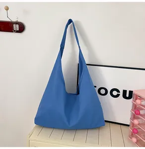 Macro detail of a blue canvas tote bag with wide shoulder straps on a wooden table