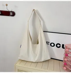 Detail view of a cream canvas tote bag hanging on a hook in a minimalist room