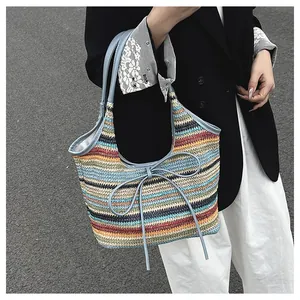 Détail du sac cabas tissé à rayures colorées avec garniture en cuir bleu et petit nœud