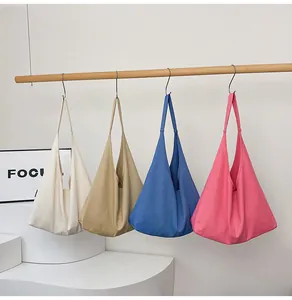 Row of canvas tote bags in cream, khaki, royal blue and rose pink colors hanging in a row
