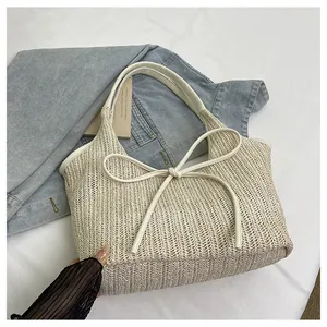 Détail du tissage en chevrons du sac en paille crème avec un grand nœud en cuir