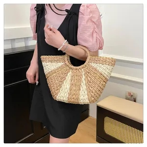 Détail du sac cabas en paille tressée avec design bicolore beige et poignées rondes