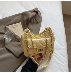 Dettaglio della borsa a tracolla trapuntata crema con chiusura rotante in metallo oro