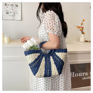 Détail d'un sac cabas tissé main bleu et blanc avec bordure dorée et anses rondes