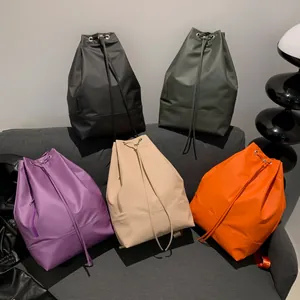 Leichter Kordelzug-Rucksack in fünf Farben auf einem Sofa für den Stadtpendler