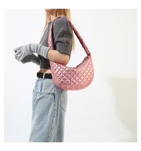 Detail view of the pink metallic quilted crescent shoulder bag styled with a grey sweater