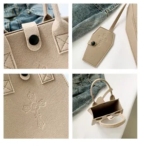 Detail view of beige felt bucket bag with gothic cross embossing and coffin charm accessory