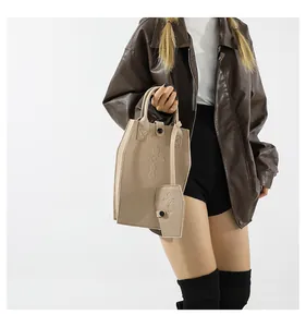 Model carrying beige coffin-shaped handbag and mini pouch set with embossed cross