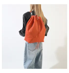 Detailansicht eines orangefarbenen Nylon-Rucksacks mit Kordelzug und vertikalen Reißverschlüssen