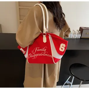 Detail of red canvas tote bag with white lettering and mesh texture on a model