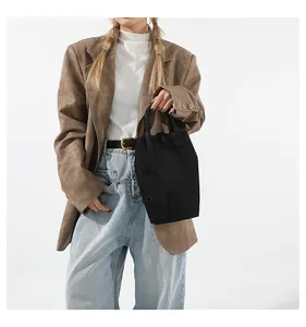 Black minimalist tote bag with small pouch held by model in stylish commute outfit