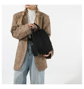Detail of a minimalist black large capacity tote bag with dual handles and charm pendant