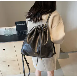 Detail of grey leather bucket backpack with drawstring closure and fashion logo text