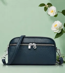 Détail du sac bandoulière en cuir grainé bleu marine montrant les fermetures éclair argentées