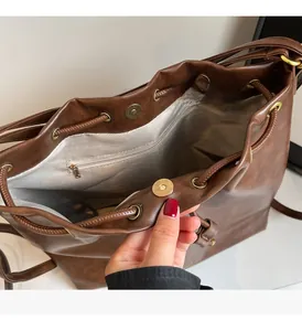Detailed interior of brown bucket bag showing herringbone lining and bronze hardware
