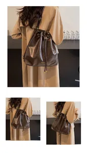 Detail of dark brown bucket bag with shiny faux leather texture and drawstring closure