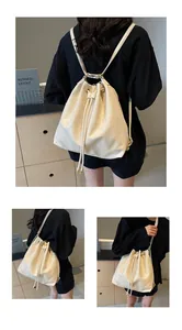 Detail showing versatile cream bucket bag worn as backpack and shoulder bag with drawstring