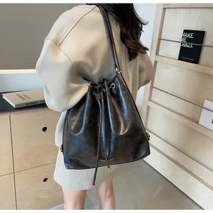 Detail view of large black bucket bag with drawstring closure and gold fashion logo