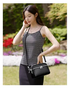 Détail d'un sac bandoulière en cuir noir grainé avec double fermeture éclair argentée