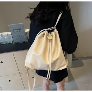 Detail view of the cream bucket bag with drawstring closure shown on model back