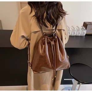 Brown PU leather bucket backpack with drawstring closure shown on model's back